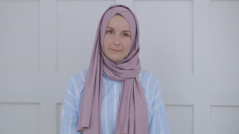 Looking-at-the-camera-and-nodding-her-head-a-Muslim-woman-in-a-hijab-is-talking-on-a-video-link-and-listening-to-a-lecture.-Remote-video-conversation